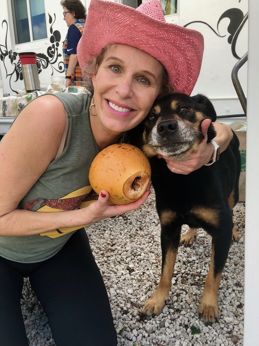 A woman in a pink hat hugging a rescued dog outdoors